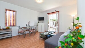 A living room with a sofa, dining table, chairs, a TV, and a plant. - Apartment 785 (Pula)