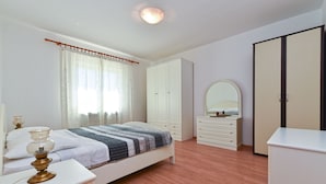 A bedroom with a bed, a dresser, a wardrobe, a mirror, and a bedside table. - Apartment 785 (Pula)