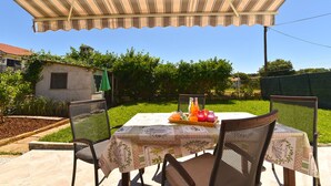 An outdoor table set with a tablecloth, chairs, and a bottle of orange juice. - Apartment 785 (Pula)
