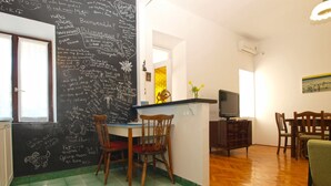 A dining area with a table and chairs, a television, and a chalkboard with writings. - Apartment 792 (Pula)