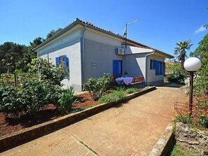 A two-story building with a tiled roof, a small garden with plants and a bench, and a paved pathway leading to the entrance. - Apartment 792 (Pula)