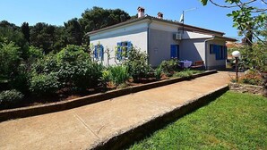 A white building with blue shutters, a paved pathway, and lush greenery. - Apartment 792 (Pula)
