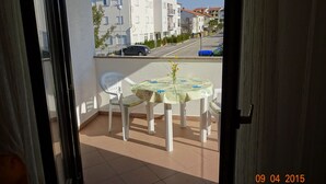 A balcony with a table and chairs, overlooking a residential street with houses and parked cars. - Apartment 802 (Porec)