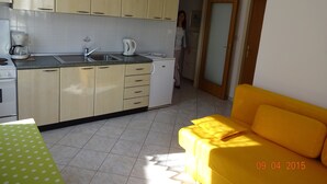 A kitchen with beige cabinets, a sink, and a coffee maker. There is a yellow sofa in the living area. - Apartment 802 (Porec)