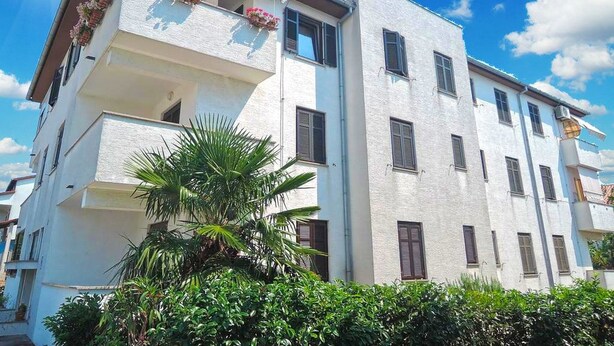 A multi-story building with balconies, a clear sky, and lush greenery in the foreground. - Apartment 802 (Porec)