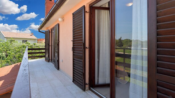 Un balcon avec un sol carrelé, une cheminée en briques et une vue sur la maison voisine.