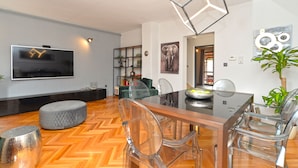 A modern dining area with a glass table, clear chairs, and a herringbone wood floor. - Apartment 843 (Fazana)