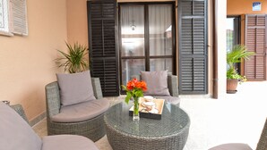 A cozy outdoor seating area with wicker furniture, a glass table, and a vase of flowers. - Apartment 843 (Fazana)