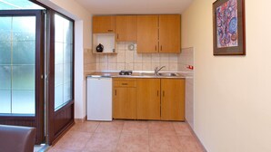 Eine kompakte Küche mit Holzschränken, einem Spülbecken und einem kleinen Kühlschrank.