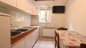 A compact kitchen with a sink, stove, and a window with a curtain. - Apartment 847 (Pula)
