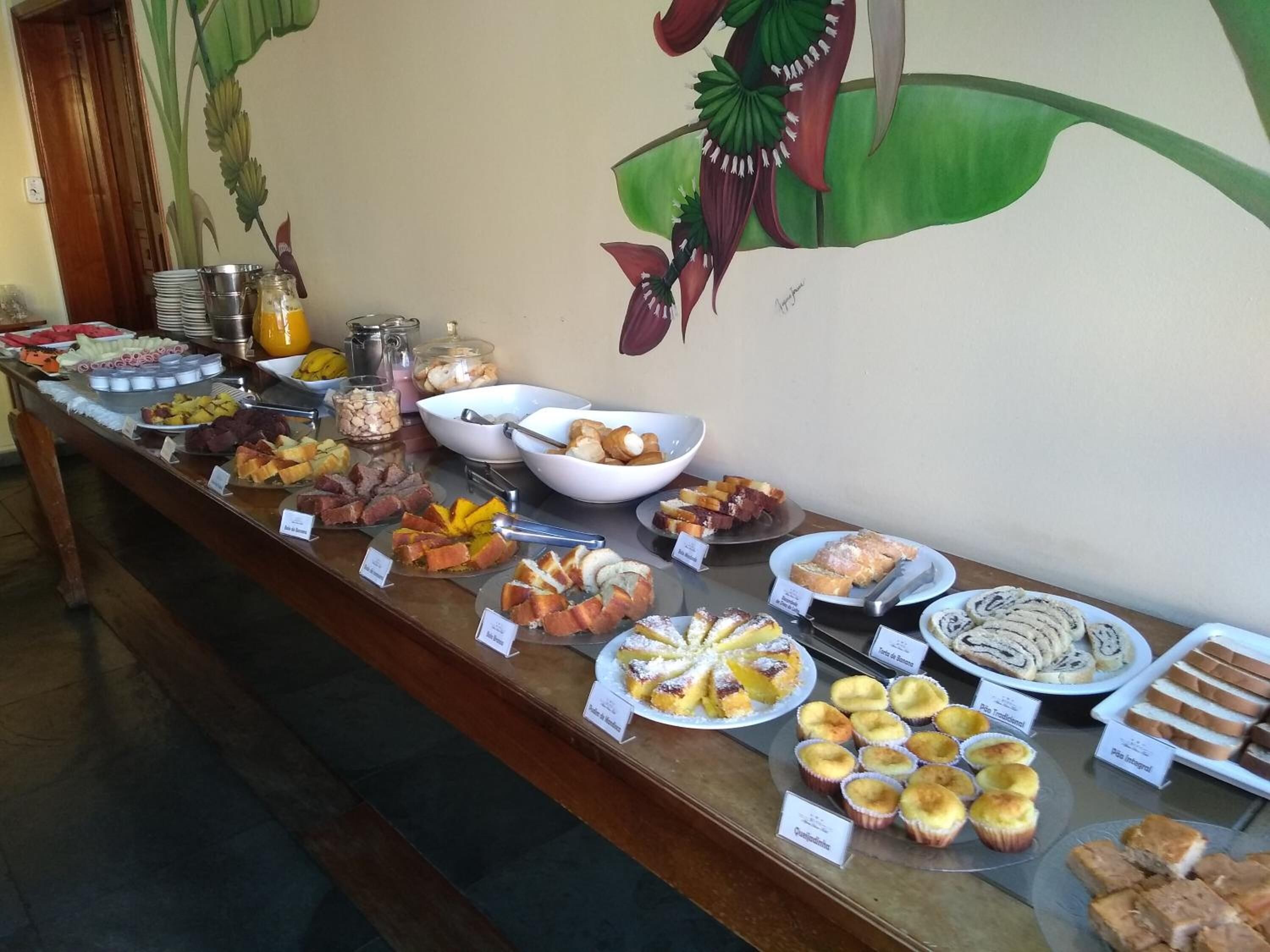 A buffet with various food items and a mural on the wall.