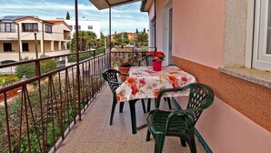 A balcony with a table and chairs, a potted plant, and a view of buildings in the background. - Apartment 860 (Rovinj)