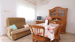 A living room with a sofa, a dining table with chairs, a TV, and a wooden cabinet. - Apartment 860 (Rovinj)