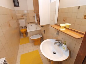 A bathroom with a toilet, bidet, sink, and mirror. - Apartment 864 (Pula)