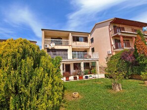 A multi-story residential building with balconies, potted plants, and a well-maintained lawn. - Apartment 864 (Pula)