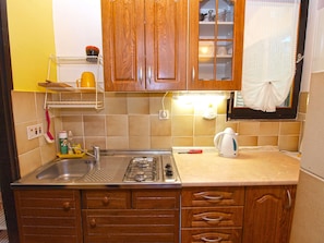 Compact kitchen with ample storage, stainless steel sink, and gas stove for practical cooking facilities.