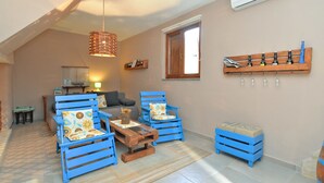 A living room with blue furniture, a wooden coffee table, and a hanging light fixture. - Apartment 877 (Pula)