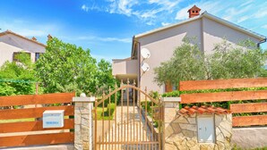 A gated entrance to a residential building with a stone wall and a wooden gate. - Apartment 877 (Pula)
