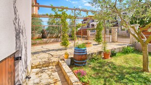 A courtyard with a pergola, potted plants, a stone bench, and a stone wall. - Apartment 877 (Pula)