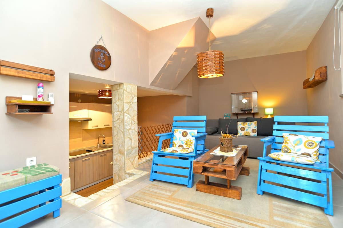 A modern living room with blue furniture, a kitchen, and a staircase.