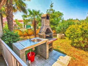 An outdoor kitchen with a stone oven, a sink, and a red bucket. - Apartment 894 (Medulin)