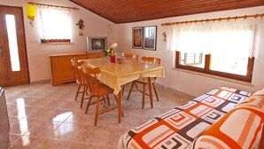 A cozy dining area with a wooden table and chairs, a television, and a window with curtains. - Apartment 895 (Medulin)