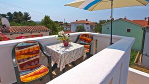 A balcony with a table and chairs, a potted plant, and a large umbrella. - Apartment 895 (Medulin)