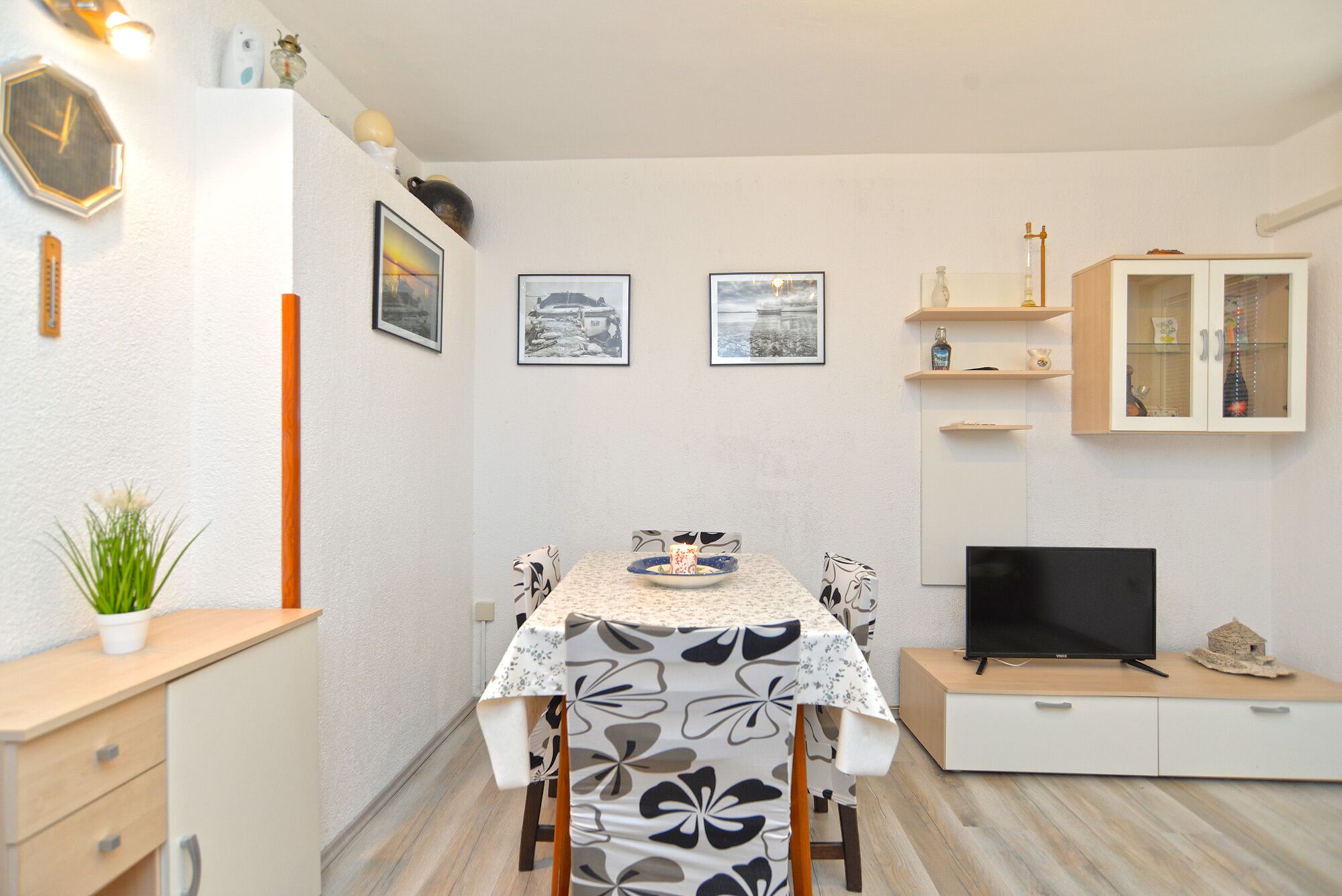 A compact living space with a dining table, chairs, a TV, and a cabinet.