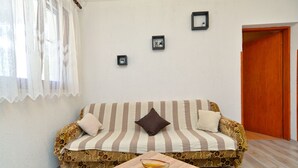 Un salon chaleureux avec un canapé à rayures, une petite table sur laquelle se trouve un bol, et une porte en bois.