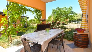 Une terrasse extérieure avec une table et des chaises, entourée de verdure et offrant une vue sur la campagne.