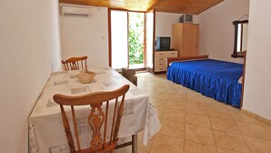 Een slaapkamer met een bed, bureau, stoel, televisie en een kledingkast.