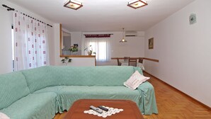 Un salon avec un canapé vert, une table basse en bois et un coin repas comprenant une table et des chaises.