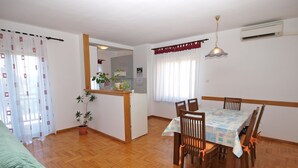 Un coin repas avec une table et des chaises en bois, une cuisine en arrière-plan et une plante en pot.