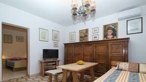 Ein Schlafzimmer mit einem Bett, einem Fernseher, einem Holzschrank und einem Esstisch mit einer Schüssel Obst.