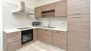 A modern kitchen with a microwave, oven, and stainless steel range hood. - Apartment 925 (Fazana)