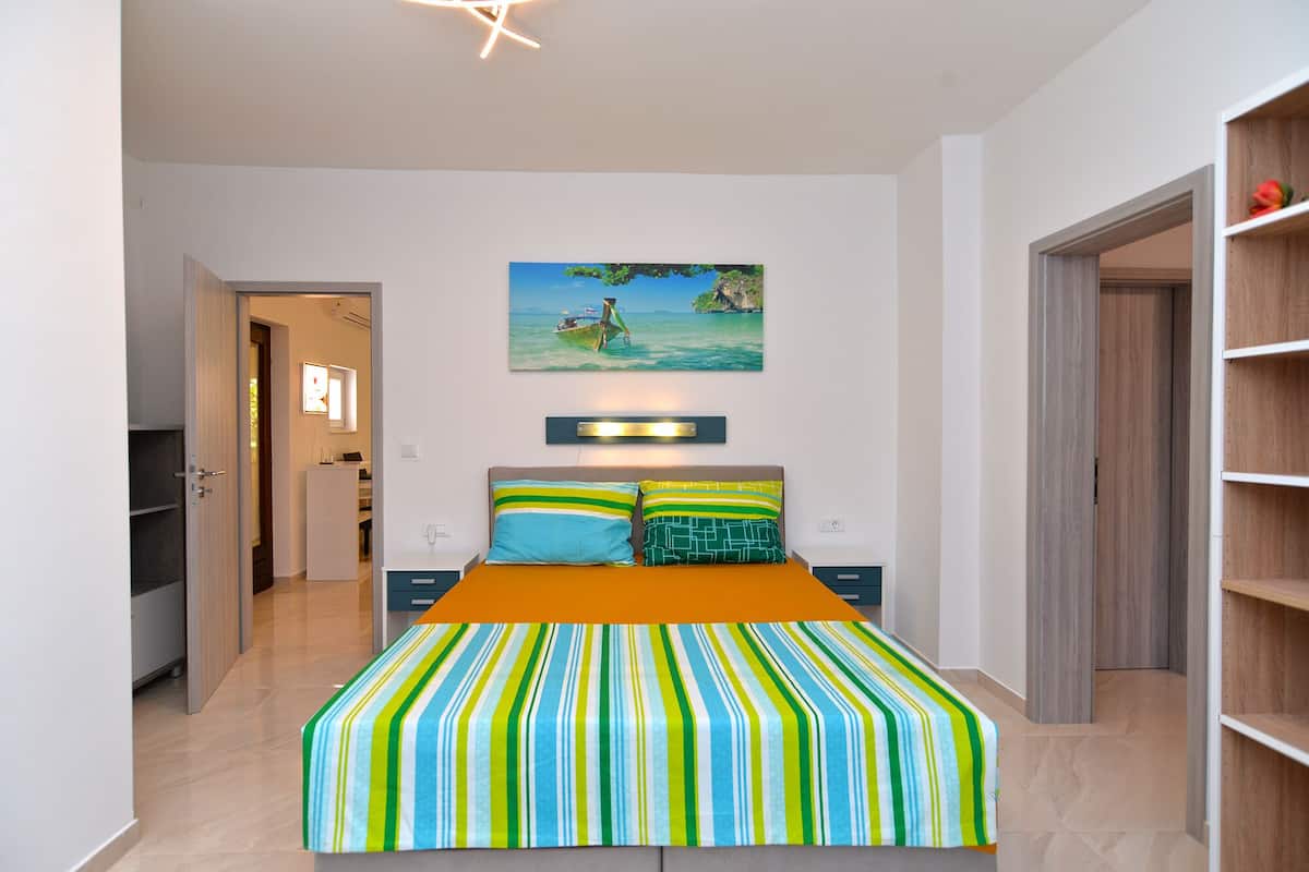 A bedroom with a bed, a painting, and a wardrobe.