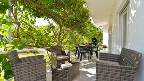 A covered outdoor seating area with wicker furniture, a table, and chairs. - Apartment 925 (Fazana)