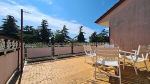 Ein Patio mit Backsteinboden, weißen Stühlen und einem Tisch.