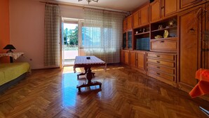 Ein Zimmer mit Holzboden, einem Esstisch mit weißer Tischdecke, Holzschränken und einer Chandelüster.