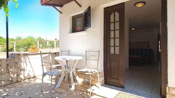 Un patio con una mesa y sillas, una puerta que da al interior y vistas del entorno.