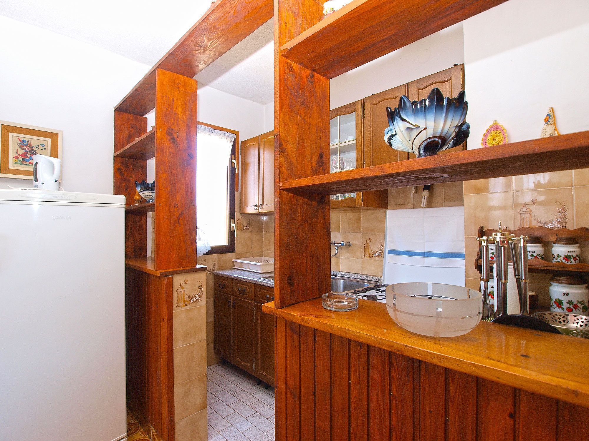A kitchen with wooden cabinets, a white refrigerator, and a window.