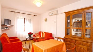 A dining area with a table set for four, a sofa, and a cabinet with glass doors. - Apartment 940 (Medulin)