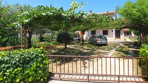 A villa with a car parked in front, surrounded by greenery and a stone pathway. - Apartment 940 (Medulin)