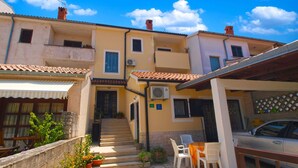 A courtyard with a staircase leading to a door, outdoor seating, and a parked car. - Apartment 946 (Pula)