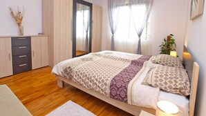 A bedroom with a bed, wooden wardrobe, and a window with curtains. - Apartment 946 (Pula)