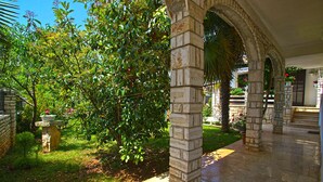 A stone pathway leading through a lush garden with a stone pillar and an archway. - Apartment 959 (Vodnjan)