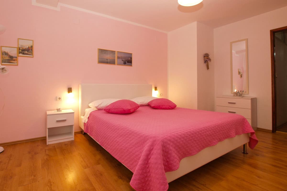 A bedroom with a bed, bedside tables, a dresser, and a mirror.