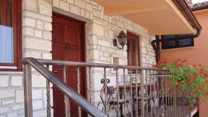 A stone building with a wooden door and a metal railing. - Apartment 990 (Fazana)