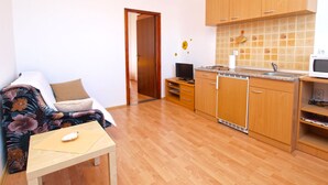 A compact living space with a kitchenette, a sofa, a small table, and a TV. - Apartment 990 (Fazana)