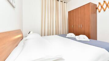 A hotel room with a bed, a wooden wardrobe, a curtain, and a wall-mounted artwork.
